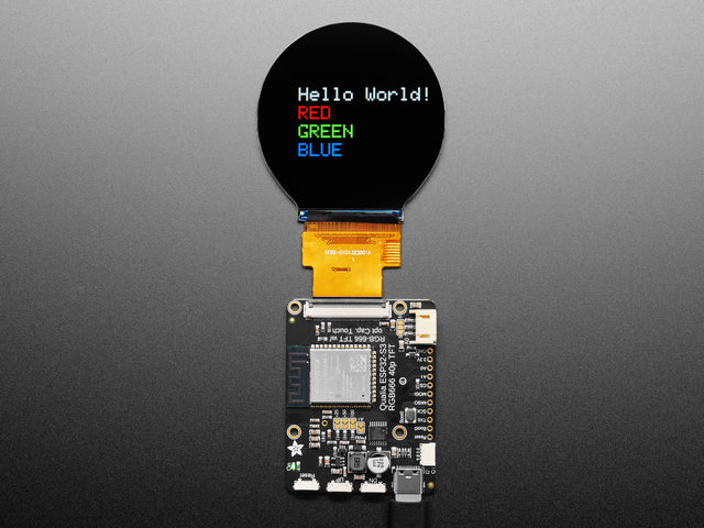 Overhead shot of TFT driver board connected to a round TFT display, which says, "Hello world!"