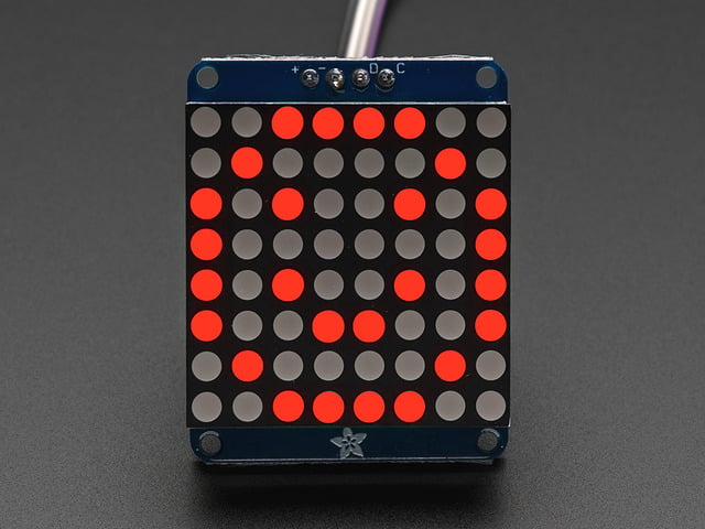 Adafruit Small 1.2" 8x8 Red LED Matrix w/I2C Backpack assembled and powered on. A red graphic smiley is displayed.