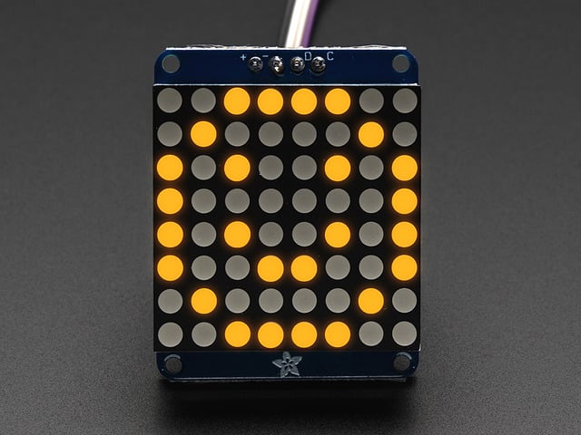 Adafruit Small 1.2" 8x8 Yellow LED Matrix w/I2C Backpack assembled and powered on. A yellow graphic smiley is displayed.