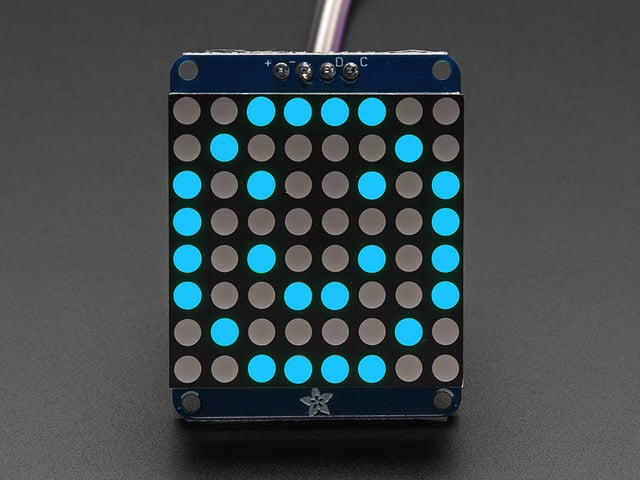 Adafruit Small 1.2" 8x8 Blue LED Matrix w/I2C Backpack assembled and powered on. A blue graphic smiley is displayed.