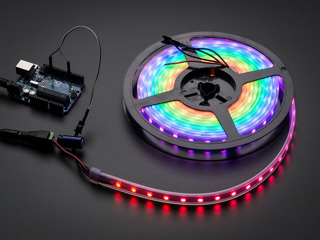 Adafruit NeoPixel Digital RGB LED Strip reel wired to a microcontroller, with all the LEDs in a rainbow