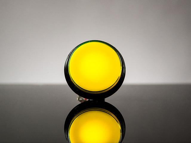 head-on shot of illuminated large yellow arcade button with LED.