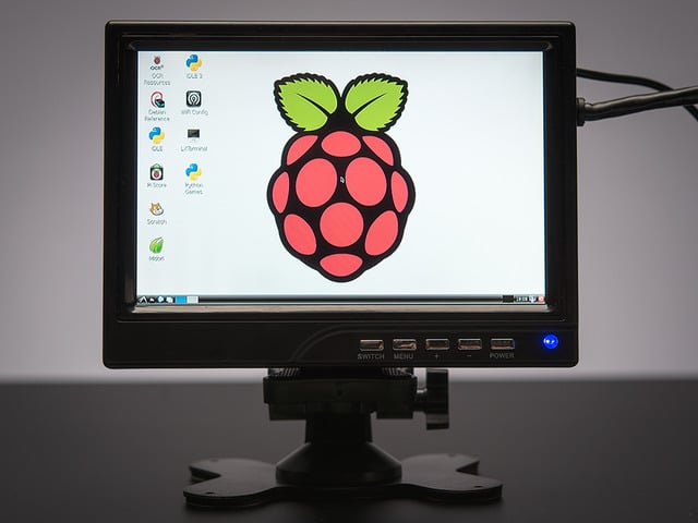 Front view of assembled and powered on HDMI 4 Pi - 7" Display. The monitor displays a desktop background with a raspberry logo.