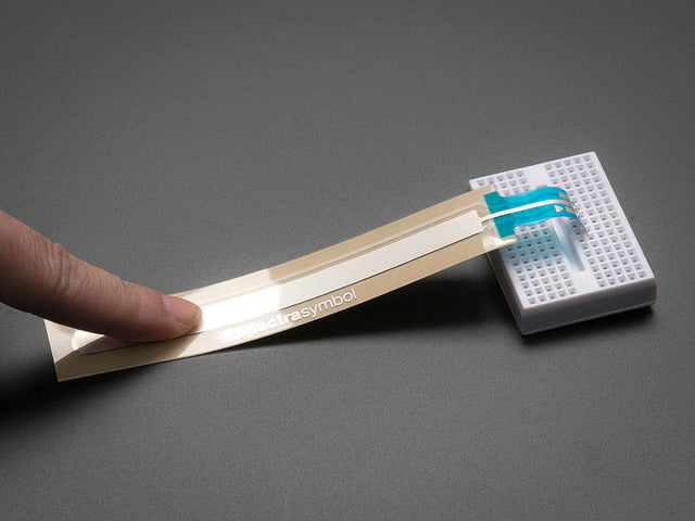 Finger pressing down on long thin FSR sensor plugged into breadboard