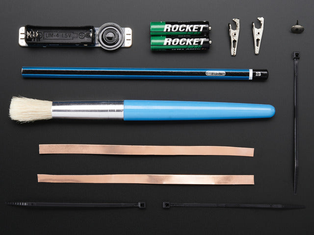 Collection of loose components in kit: assembled PCB, pencil, brush, copper tape and other parts.