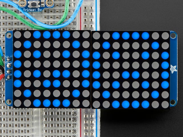 Close-up of Soldered and assembled 16x8 1.2" LED Matrix + Backpack - Ultra Bright Round Blue LEDs on a breadboard. The LED Matrices display a smiling emoji and a frowning emoji.