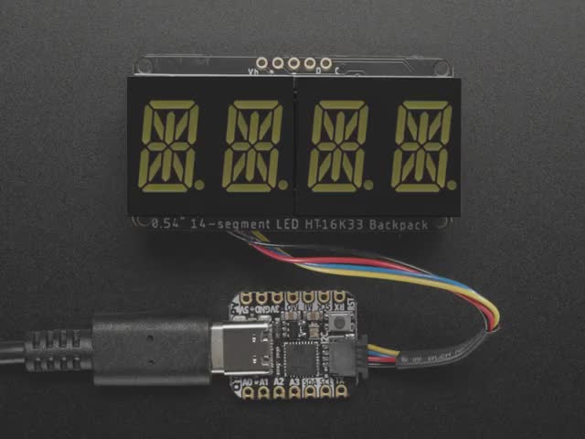 Overhead shot of an assembled 14-segment LED backpack, emitting the follow text in white LEDS: "AdaFruit 14-Segment Backpack"