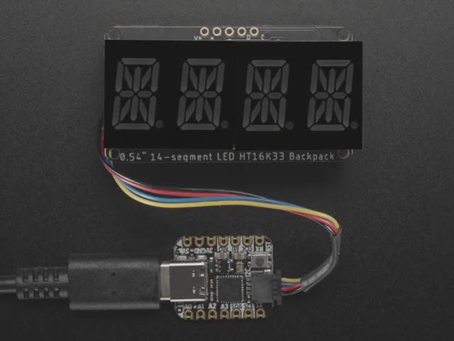 Overhead shot of an assembled 14-segment LED backpack, emitting the follow text in green LEDS: "AdaFruit 14-Segment Backpack"