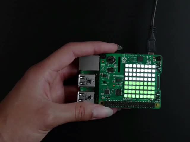 Video of a white hand tilting a  Raspberry Pi Sense HAT stacked on a Raspberry Pi. As it tilted back the LED's start to light up green. 