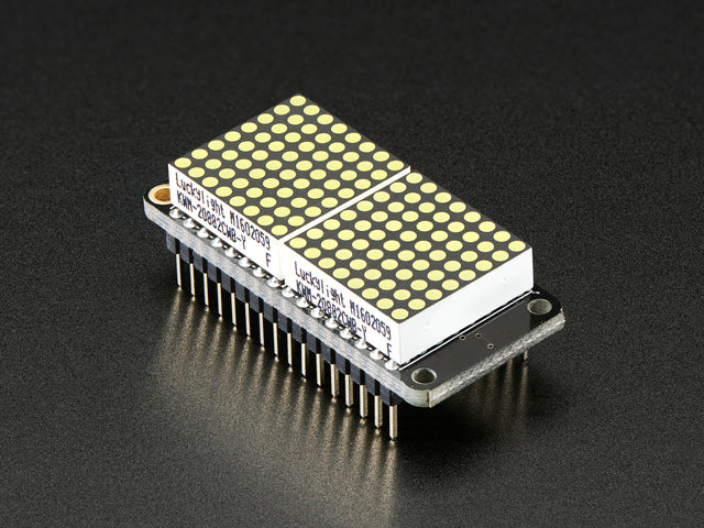 Angled shot of a rectangular shaped LED Matrix FeatherWing Display Kit breakout board with an LED matrix soldered on.