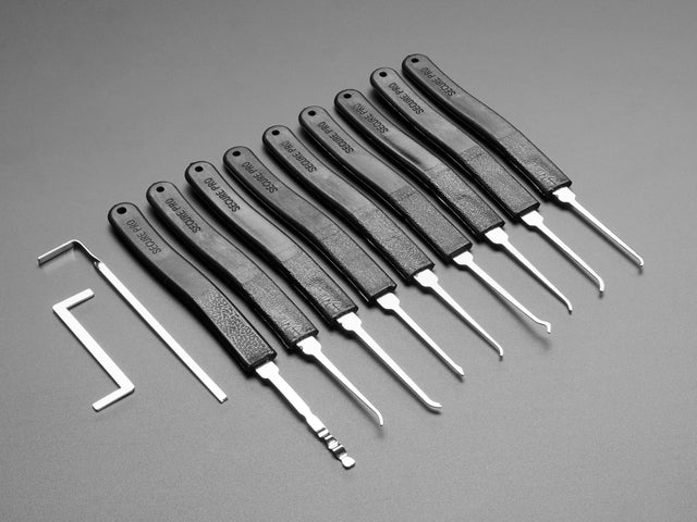 Array of many lock picks with plastic handles, plus wrenches
