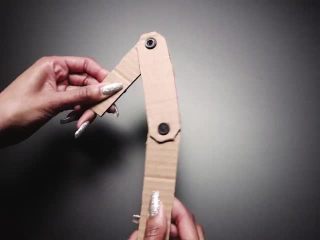 Hand twisting a three-piece hinge made with pop rivents and cardboard