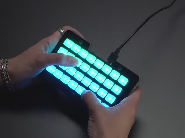Hands pressing buttons on lit up NeoTrellis M4