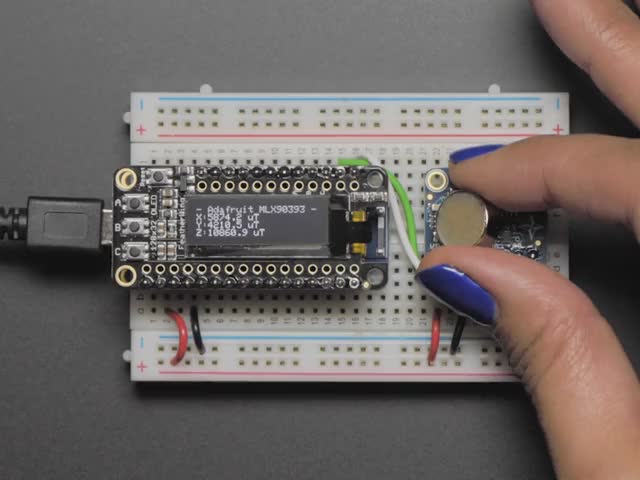 Video of a white hand with purple polished nails moving a battery above a Adafruit Wide-Range Triple-axis Magnetometer. 