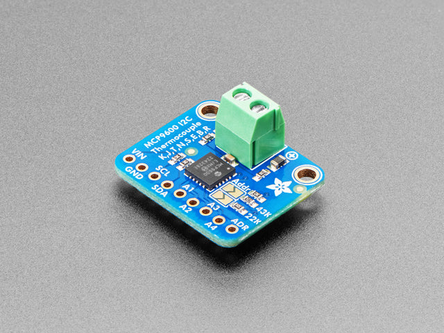 Angled shot of a square, blue, thermocouple amplifier with a green terminal block.