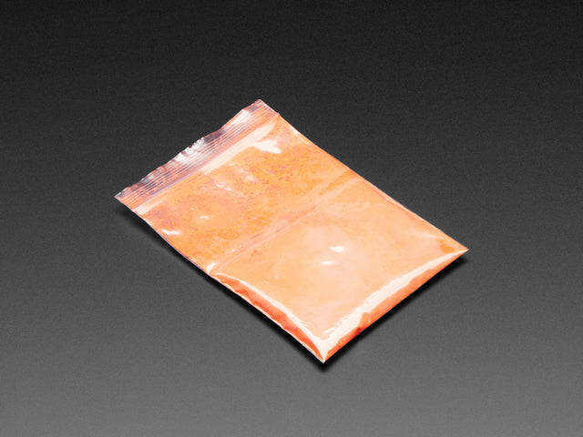 Angled shot of plastic baggy containing orange thermochromic pigment powder.