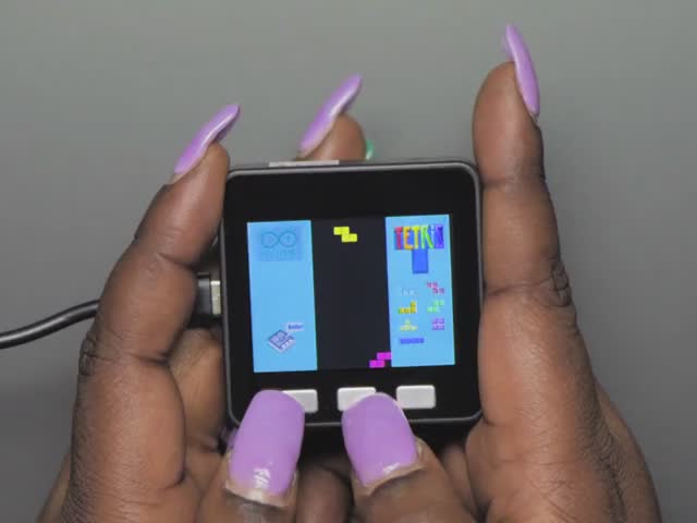 Purple polished hands playing a tetris game on a M5Stack Basic Core IoT Development Kit. 