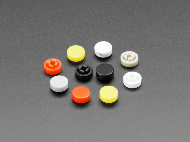 Angled shot of 10 plastic button caps colored reddish-orange, yellow, white, and black.