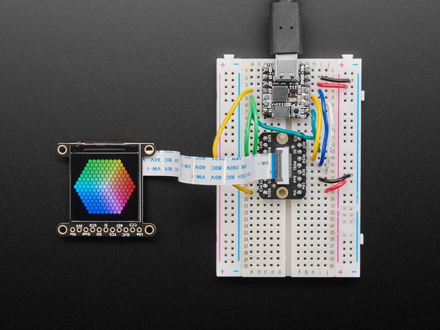 Overhead shot of 1.3" TFT breakout connected via EYESPI board and microcontroller on a half-size breadboard. The TFT breakout displays a colorful hexagon.