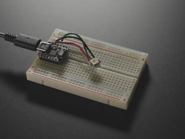 Glowing NeoPixel Mini Button PCB wired up to a microcontroller