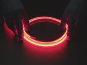 Two hands repeatedly bending and manipulating lit-up flexible red LED strip