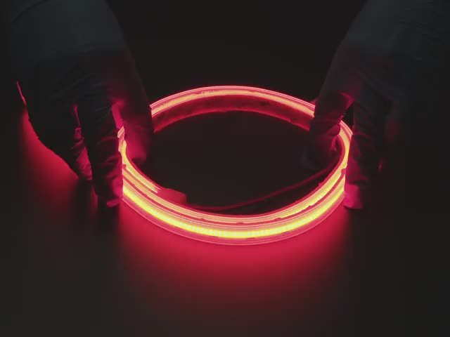 Two hands repeatedly bending and manipulating lit-up flexible red LED strip