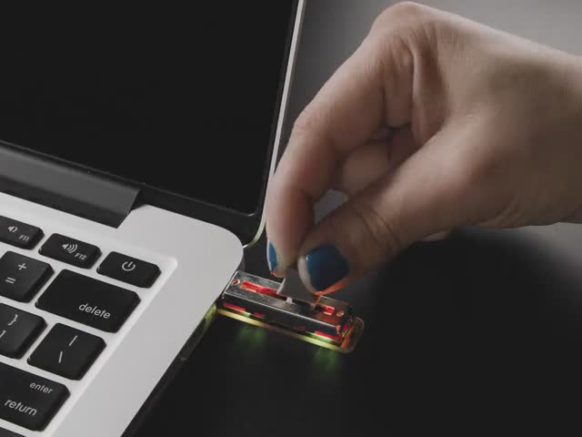 Video of a blue manicured hand sliding the potentiometer on the Slide TrinKey board. Rainbow colors cycle below the slide pot.