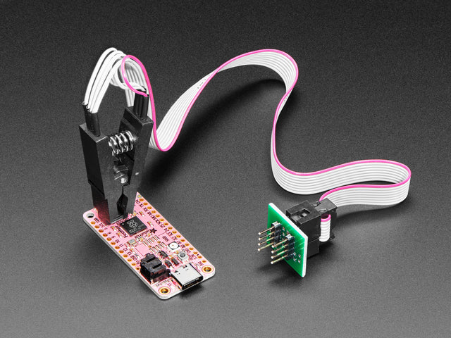 probe clip with cable attached to a SOIC chip on a pink PCB.