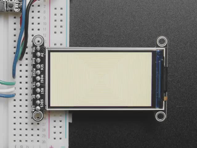 TFT display breakout soldered and assembled onto a half-size breadboard and wired up to a microcontroller. The color TFT screen displays a cycle of animations.