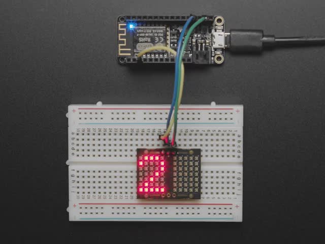 Video of an LED matrix board on a half-size breadboard counting up numbers in rainbow colors.