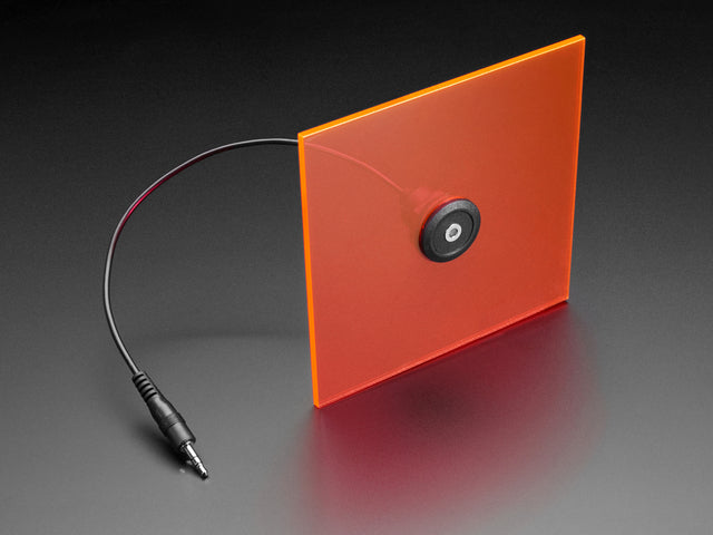 Angled shot of a panel mount stereo cable enclosed in an orange acrylic square with a hole in the middle.