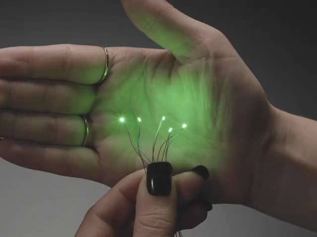 Video of a five mini wired LEDs emitting green light against a white open palm.