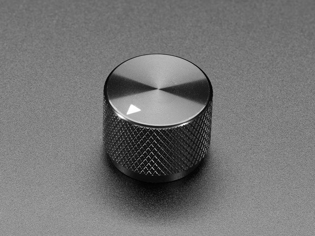 Angled shot of a black aluminum knob. A white triangle on top of the knob points at 5:00. 