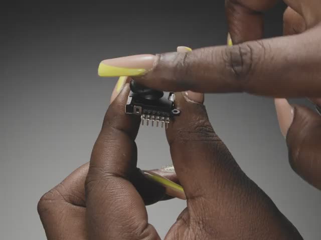 Video of a Black woman's yellow nail manicured hand manipulating a breadboard-friendly thumbstick.