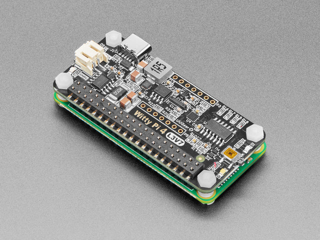 Angled shot of black rectangular power management add-on board assembled on a green microcontroller.