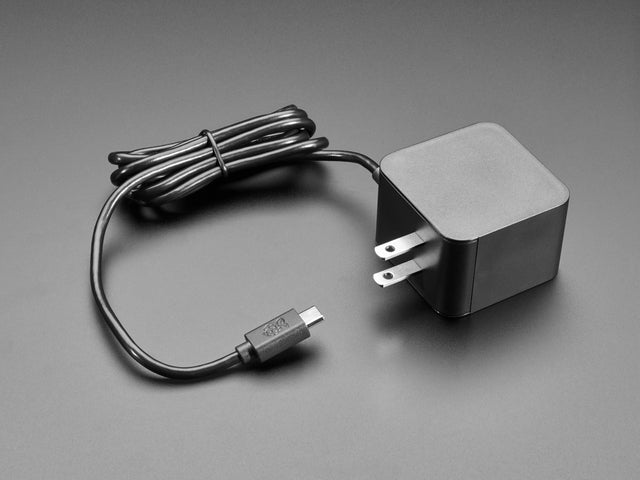 Angled shot of black, square-shaped power supply block with a coiled black cable.