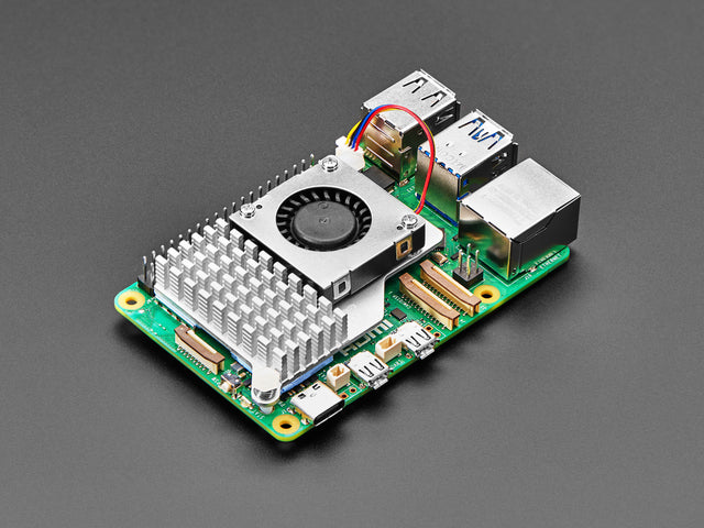 Angled shot of a cooling fan installed on a green microcontroller.