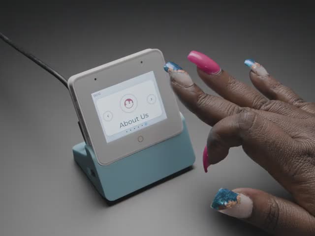Video of a Black woman's manicured hands manipulating the touchscreen on a small square-shaped LCD module.