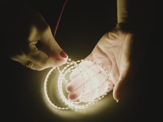 Video of a hand articulating a double-sided LED strip emitting warm white LEDs.