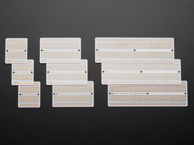 Top view of three packs of three different sized Adafruit Perma Proto-Board PCBs.